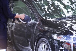 黒の車を洗車している人
