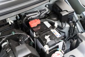 車のバッテリーと配線が見えるエンジンルームのクローズアップ