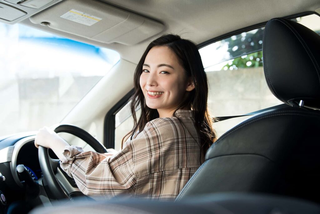 車内で運転席に座り微笑む女性ドライバー