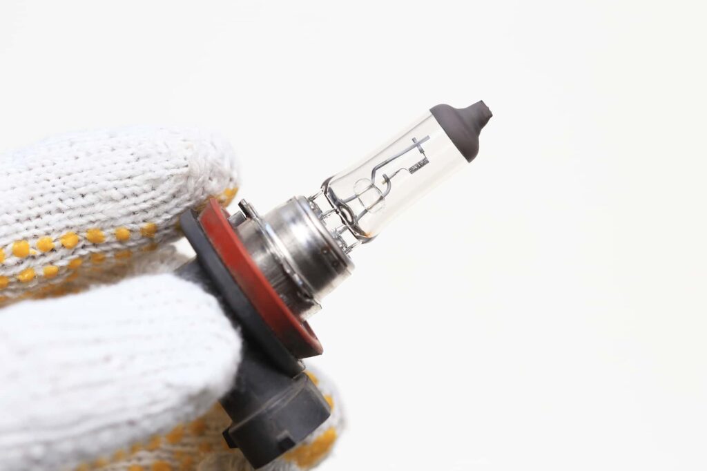 手袋をした手で持つ自動車用ハロゲンバルブ