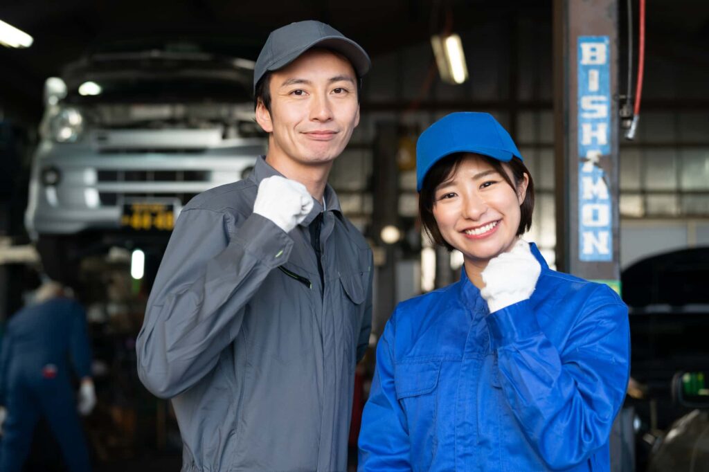 自動車整備工場で元気にポーズをとる男女の整備士