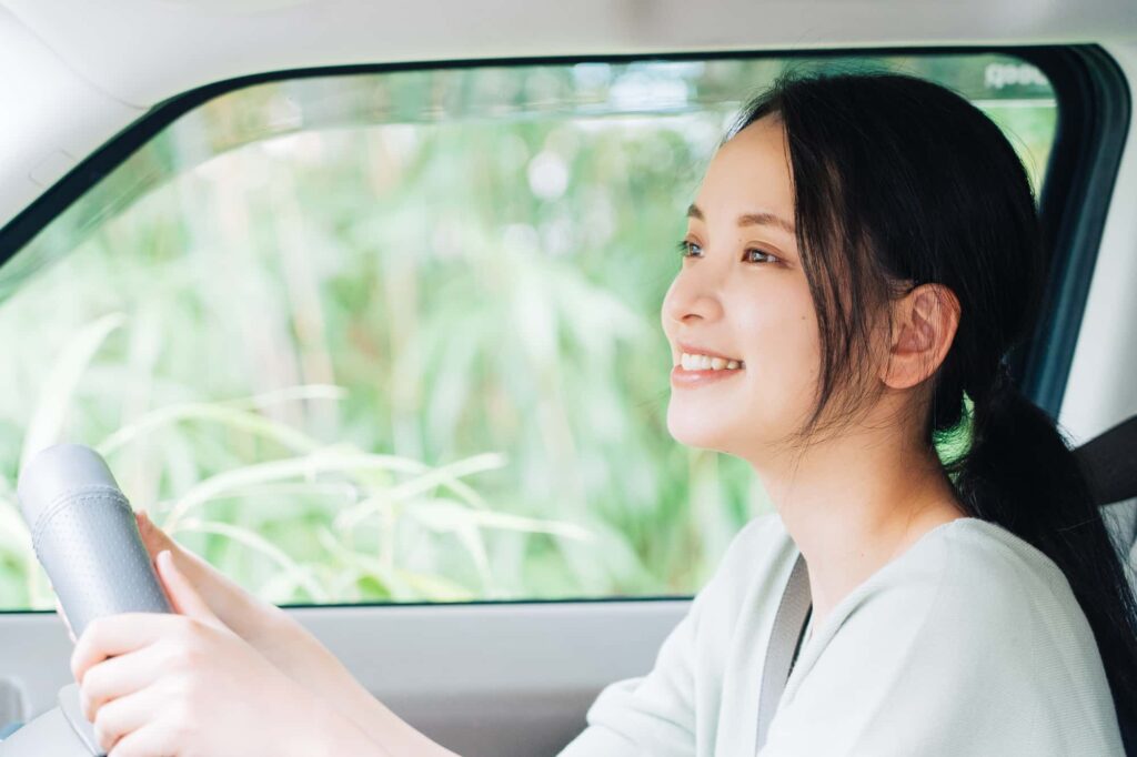 運転席で笑顔の女性ドライバーが前方を見ている様子
