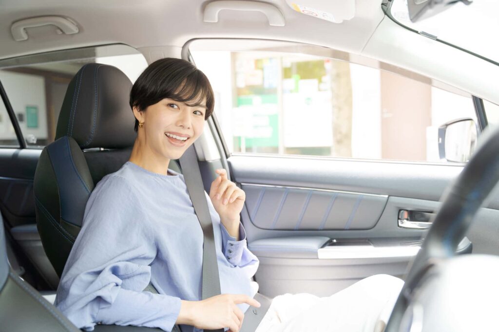 シートベルトを締めこちらを笑顔で見る女性