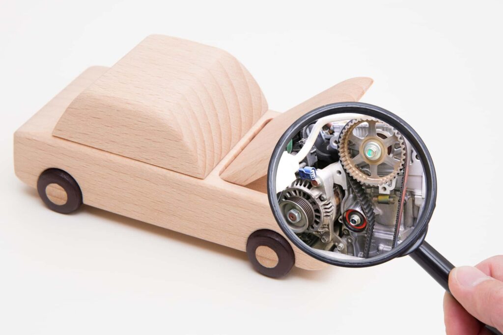木製の車とエンジン部品を写す虫眼鏡