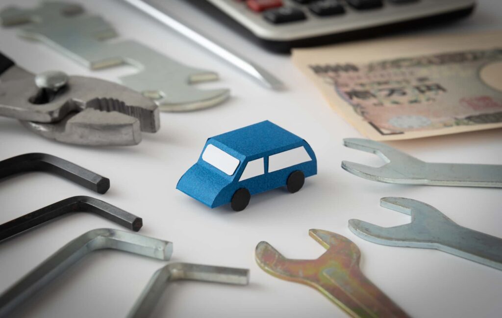 青い紙の車と工具、整備費用のイメージ