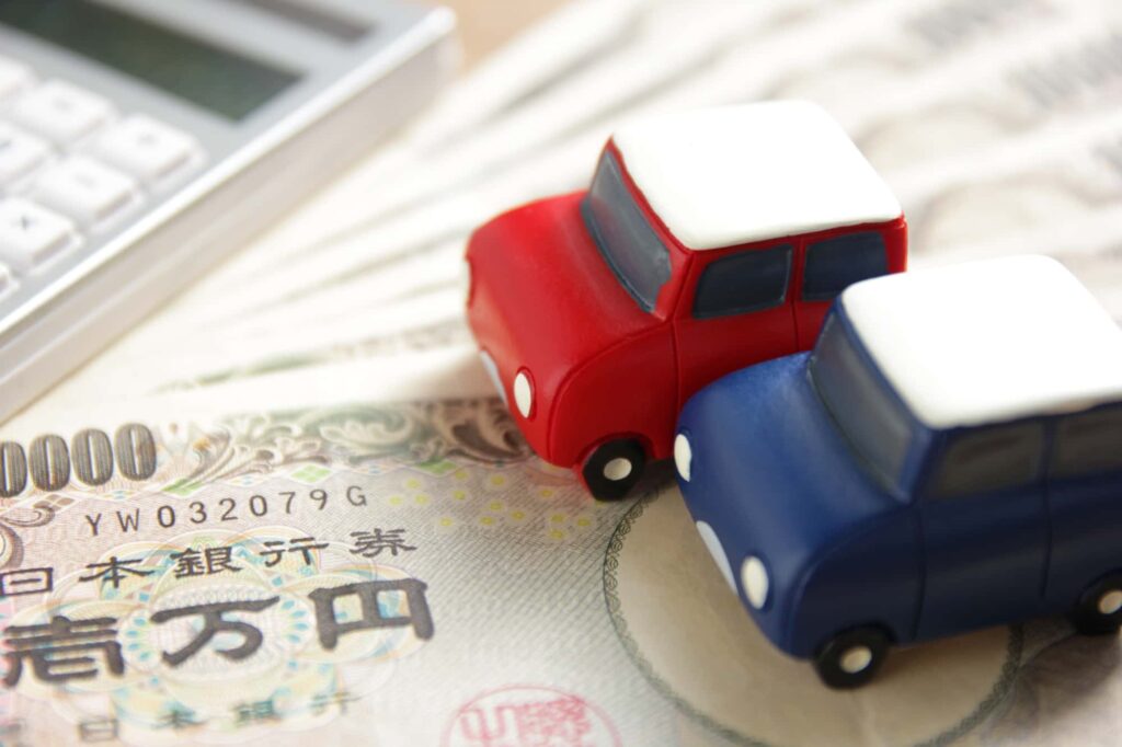 1万円札の上に置かれている2台のミニカー