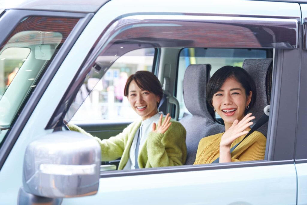車内で笑顔の女性2人がドライブ中