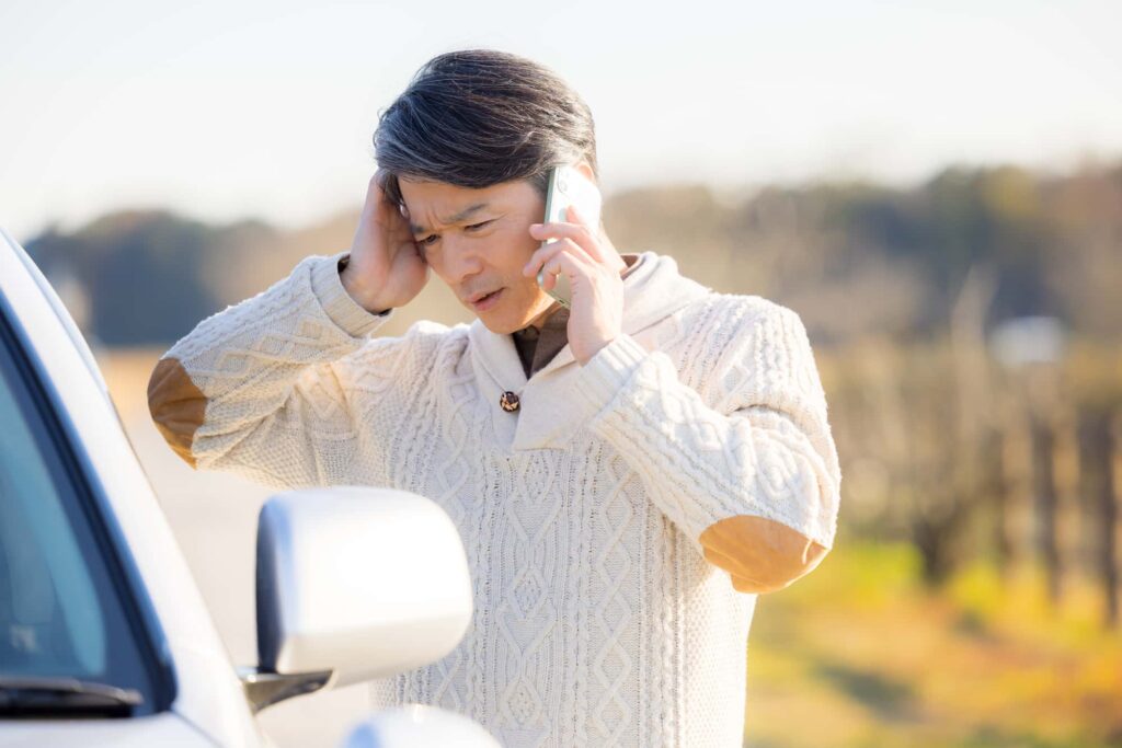車の前で頭を抱えて電話する男性