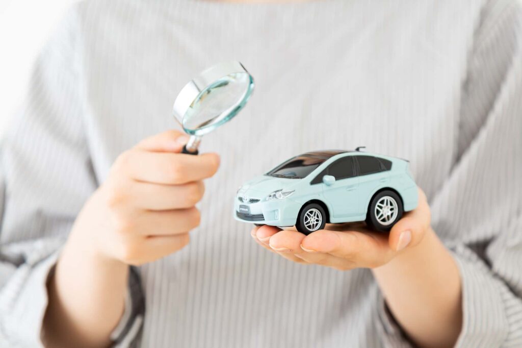 虫眼鏡とミニカーを持つ人