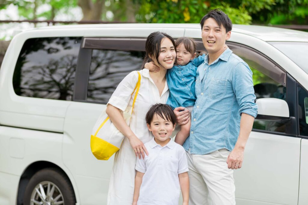 車の前に立ってこちらを見る家族