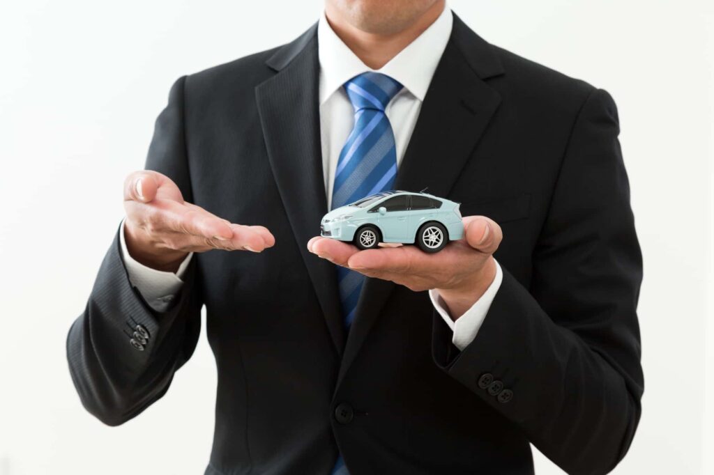 手のひらに置かれたミニカーを指す男性