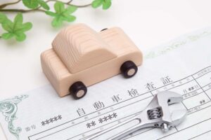 車検証の上に置かれた木でできた車のおもちゃ