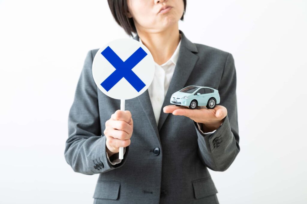 ミニカーと×のプラカードを持つ女性