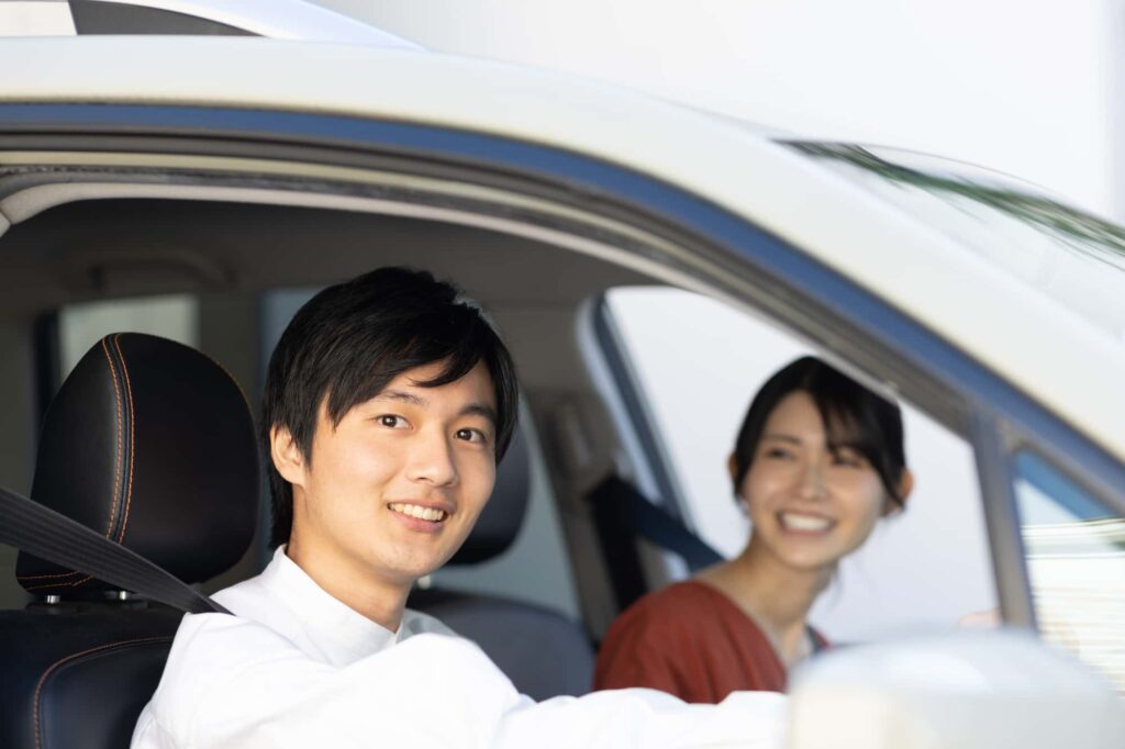 車内で笑顔の若いカップルがシートベルトを着用している様子