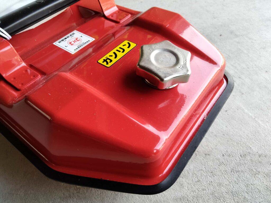 金属製の赤いガソリン携行缶と燃料キャップのクローズアップ
