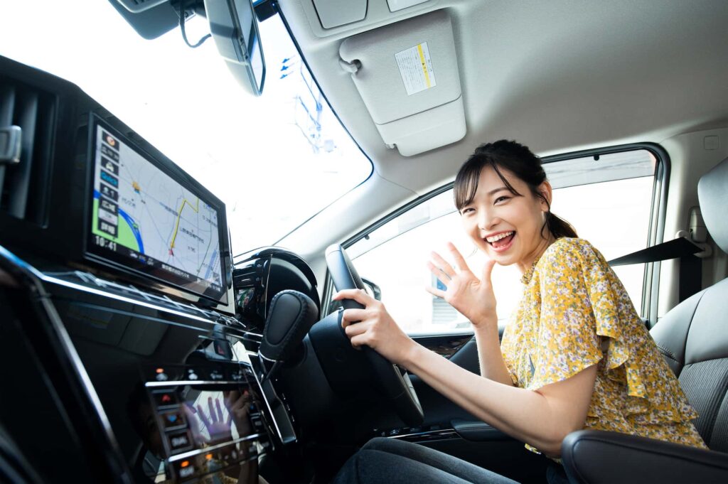 ハンドルを握って笑顔でこちらを見る女性