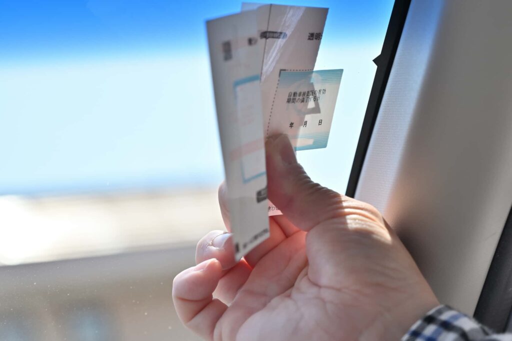 自動車検査証のシールを貼る手