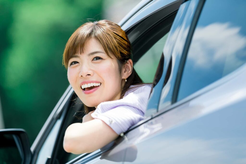 笑顔で窓から顔を出す女性ドライバー
