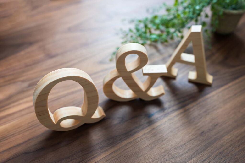 木製のQ&Aの文字と観葉植物が木製の机に置かれている