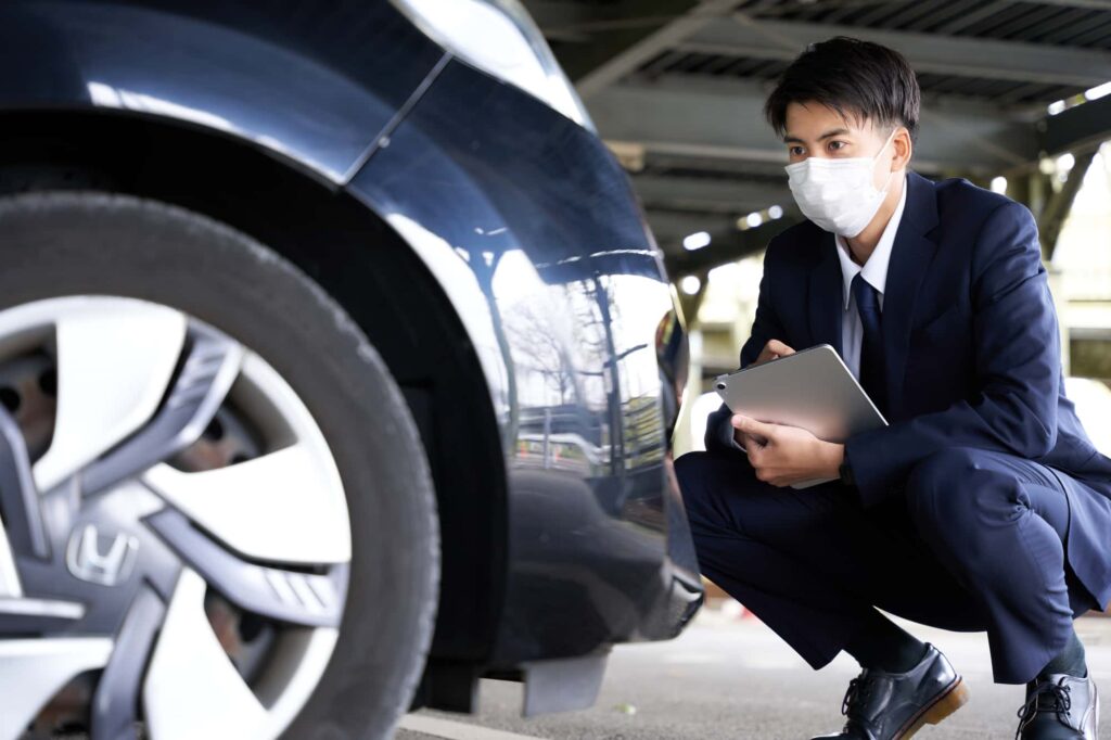 車を点検するマスク姿のビジネスマン