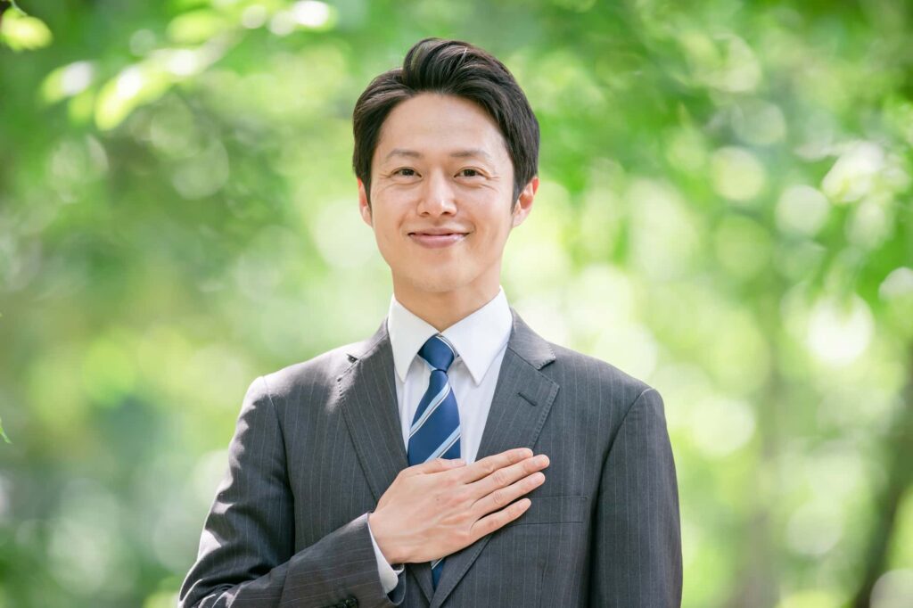 胸に手を当てて微笑むビジネスマン