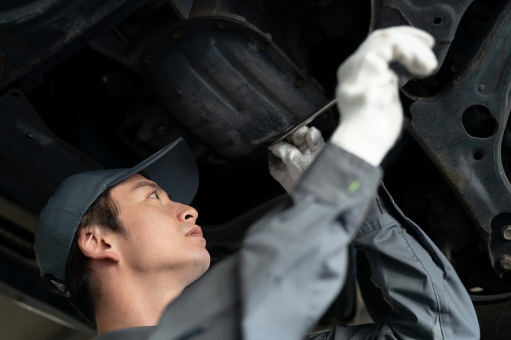 車の底を点検する整備士
