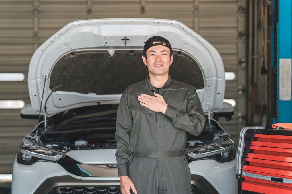 車の前で胸に手を当てる整備士